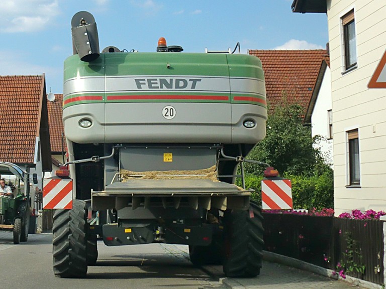 Ein großes Landfahrzeug von hinten auf einer innerörtlichen Straße