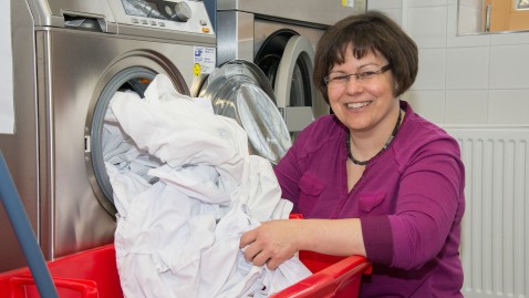 Frau sortiert Wäsche aus einer Waschmaschine