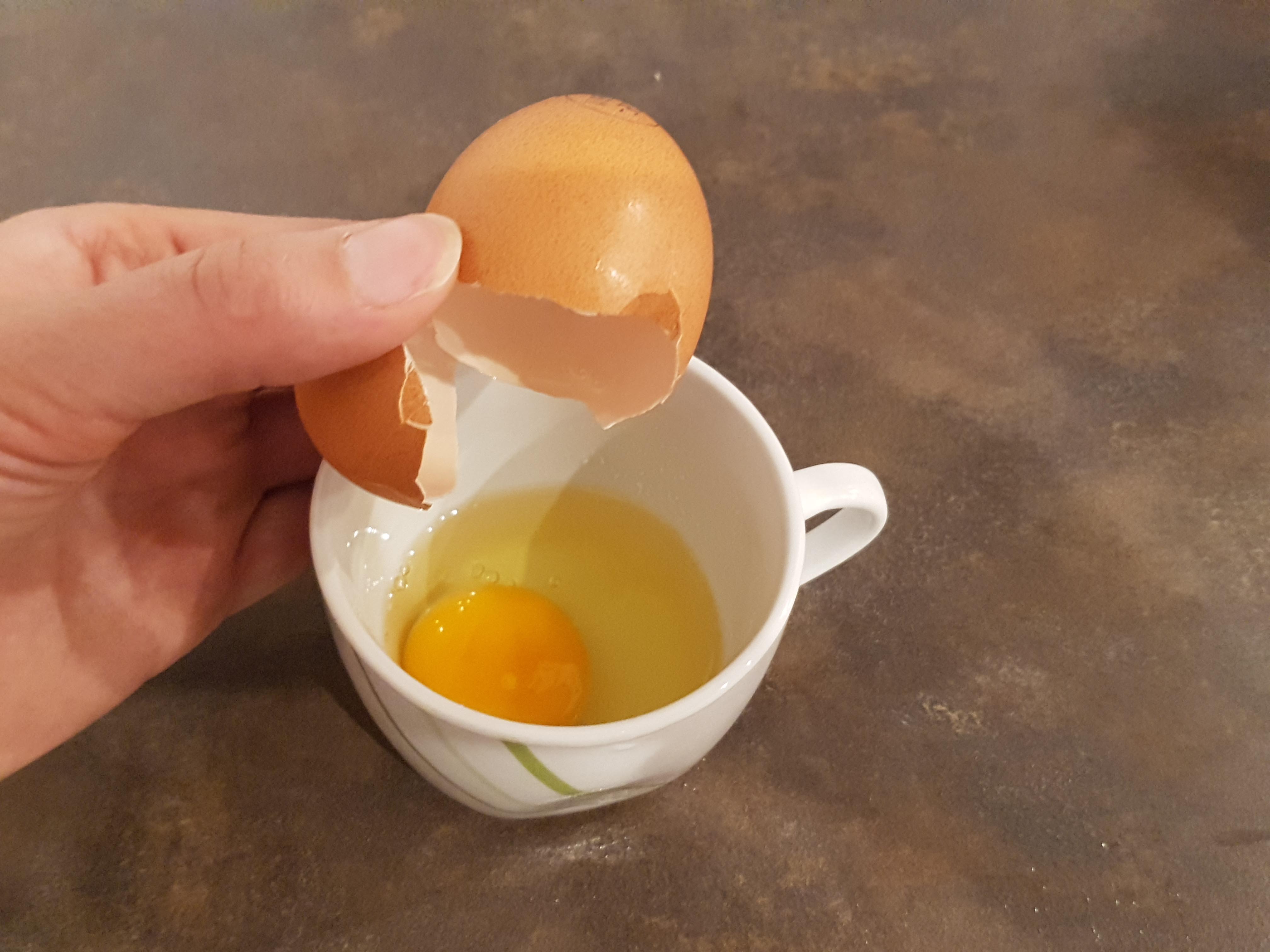 Ein Ei in die Tasse aufschlagen.