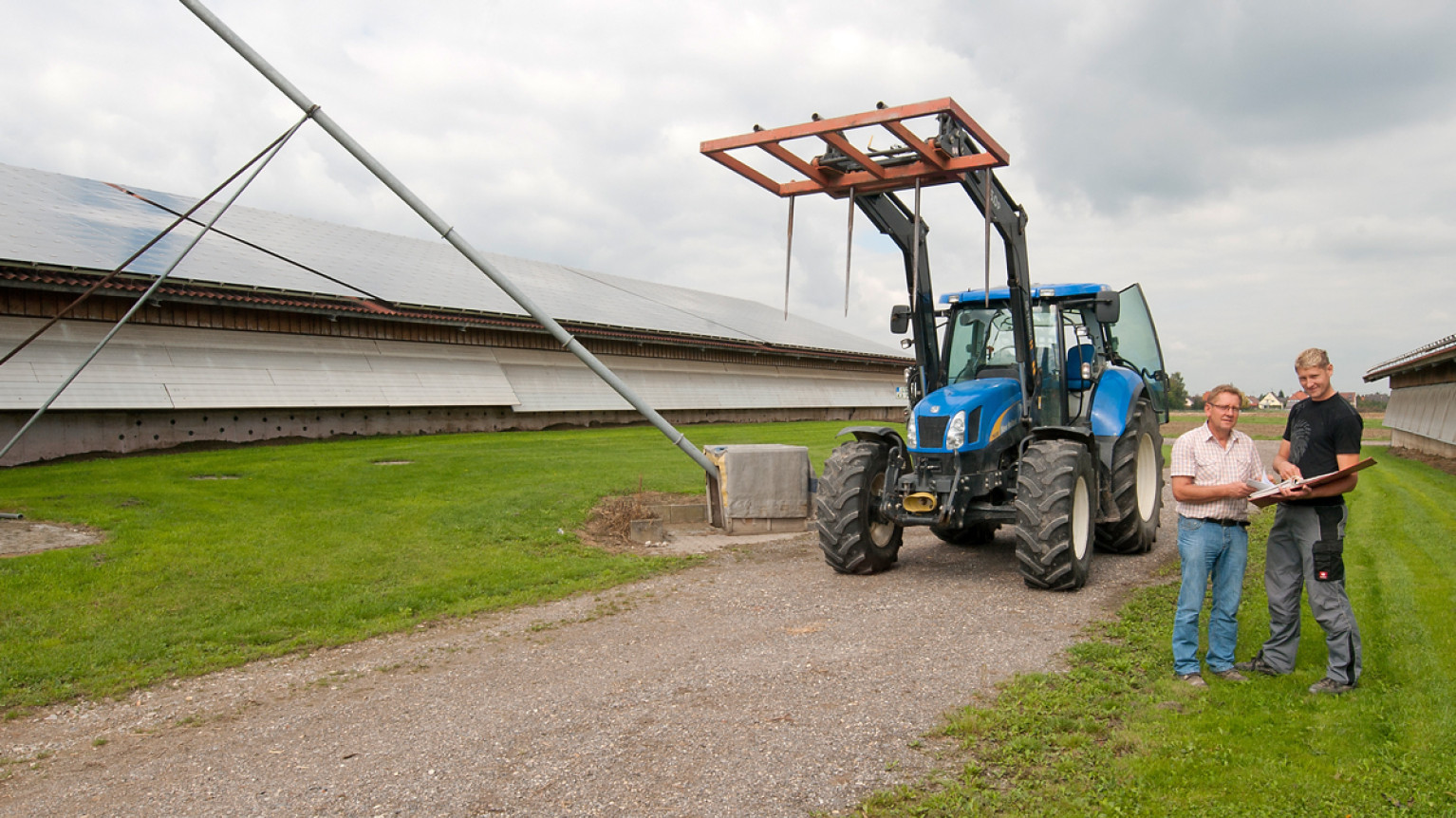 Zwei Landwirte vor ihrem Traktor bei der Arbeit