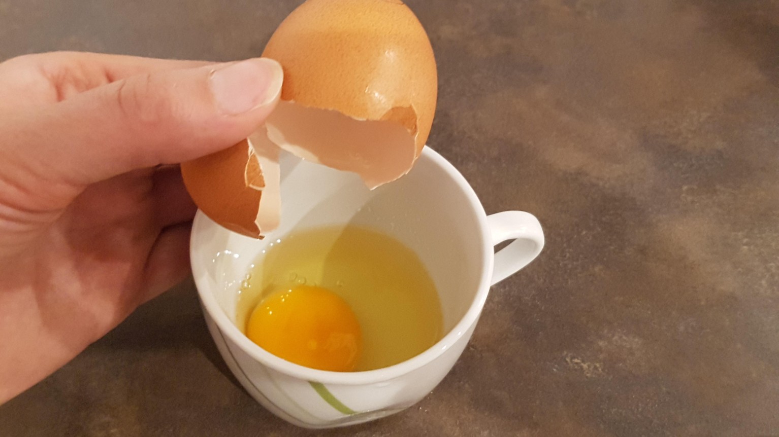 Ein Ei in die Tasse aufschlagen.