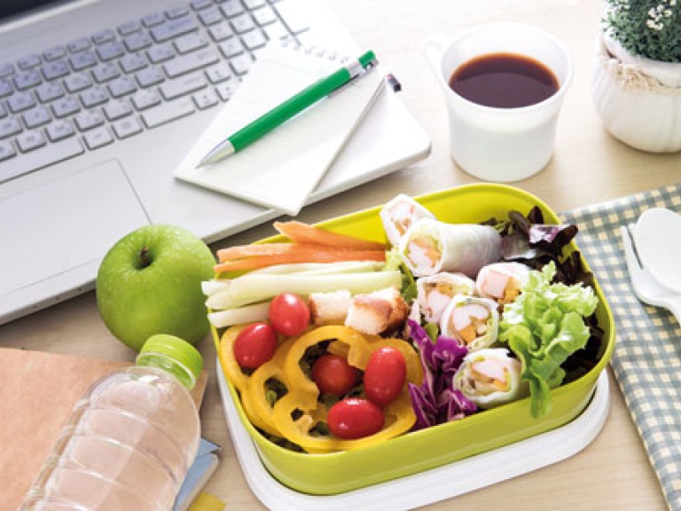 Lunchbox mit gesunden Snacks auf einem Schreibtisch mit Laptop