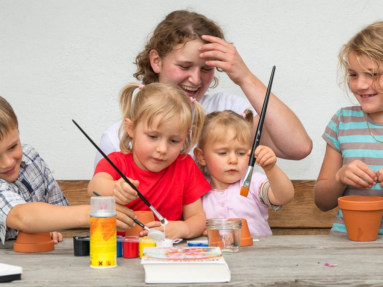 Kinder spielen mit Wassermalfarben an einem Tisch