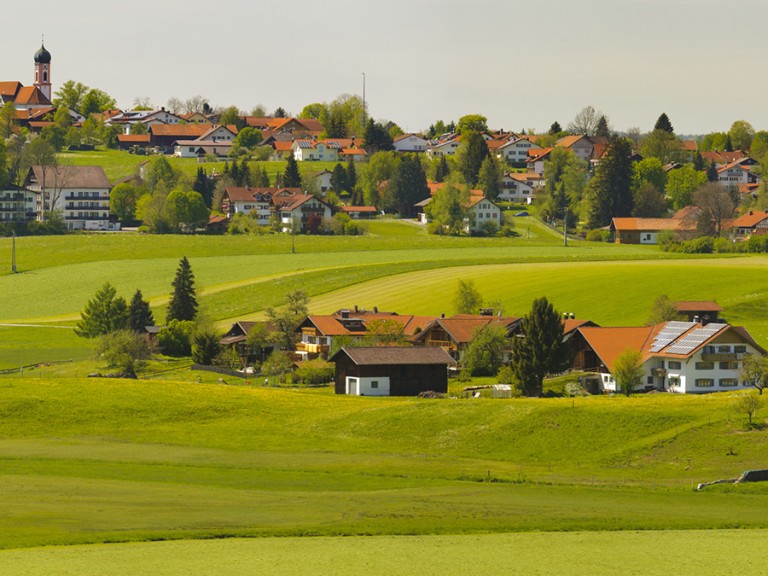 Landschaft in Bayern mit Dorf, Bauernhöfen und grünen Wiesen