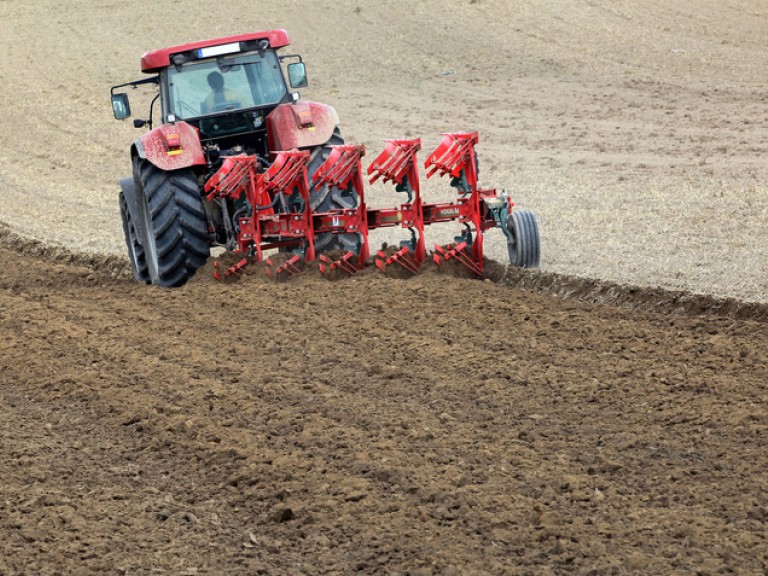 Traktor zieht pflug über einen Acker