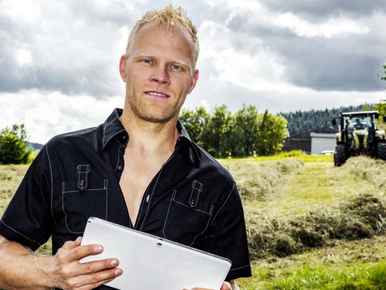 Junger Landwirt steht mit seinem Tablet-Computer auf seinem Feld