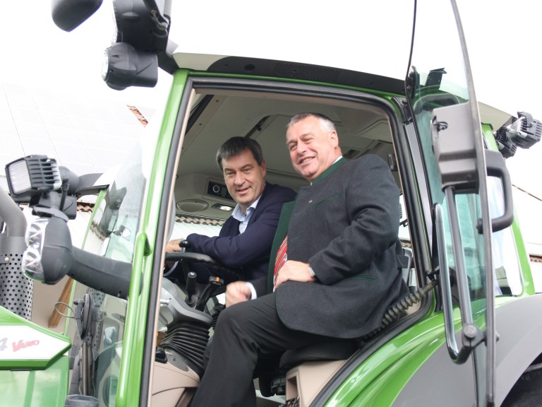 Bauernpräsident Heidl und Ministerpräsident Söder sitzen auf einem Schlepper mit RTK Signal