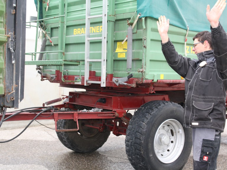 Ein angegendet Landwirt bei der Einweisung eines Anhängers