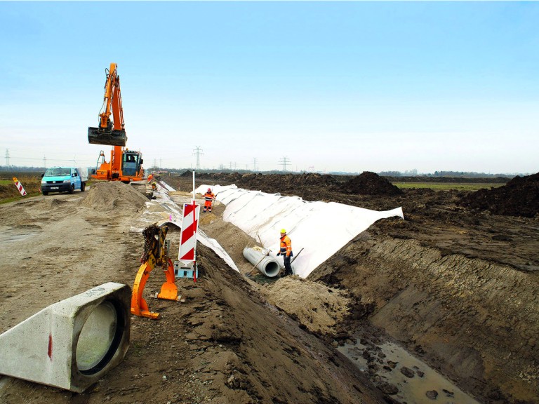 Bagger und Bauarbeiter heben eine lange Grube aus