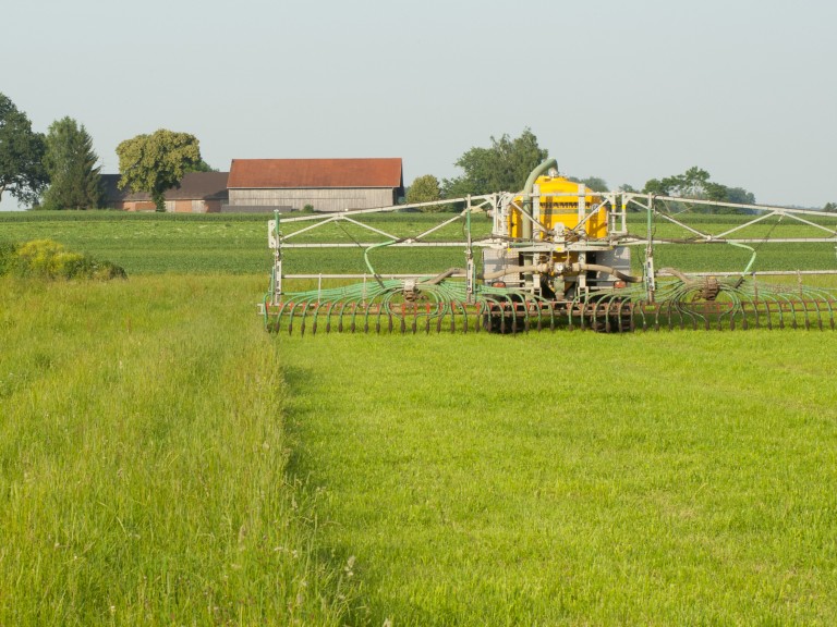 Ein Schlepper düngt auf einer grünen Wiese