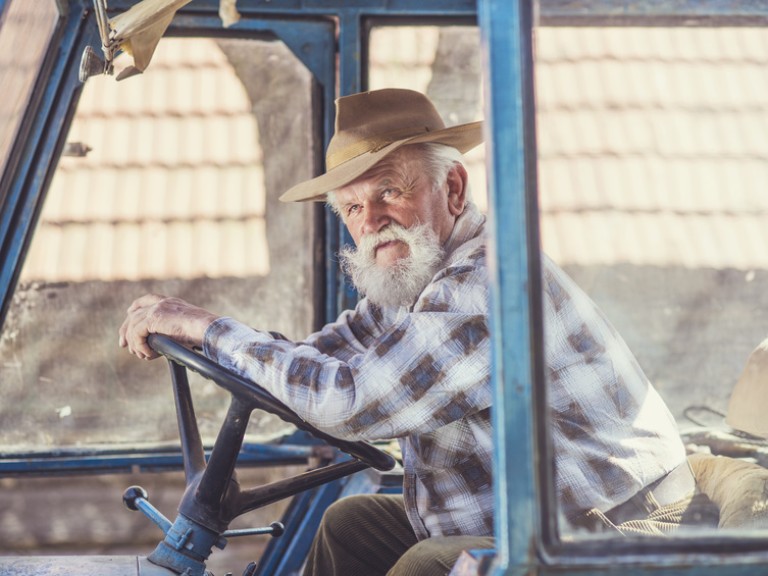 Ein alter Rentner sitzt im Traktor
