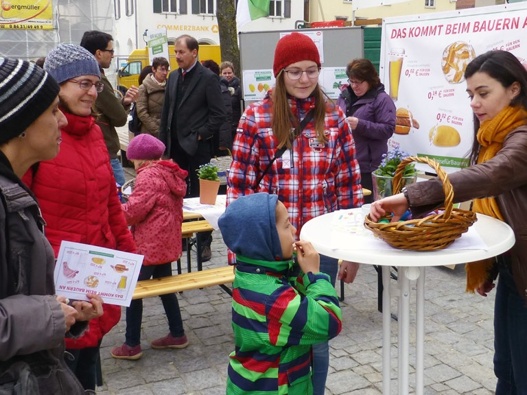 Die Landfrauen im aktiven Gespräch mit Verbrauchern an einem Informationsstand am Markplatz.