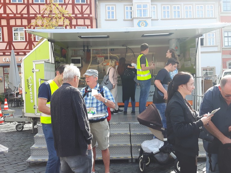 Menschen auf dem Marktplatz vor dem Schweinemobil