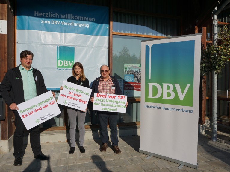 Drei Personen mit Plakaten demonstrieren