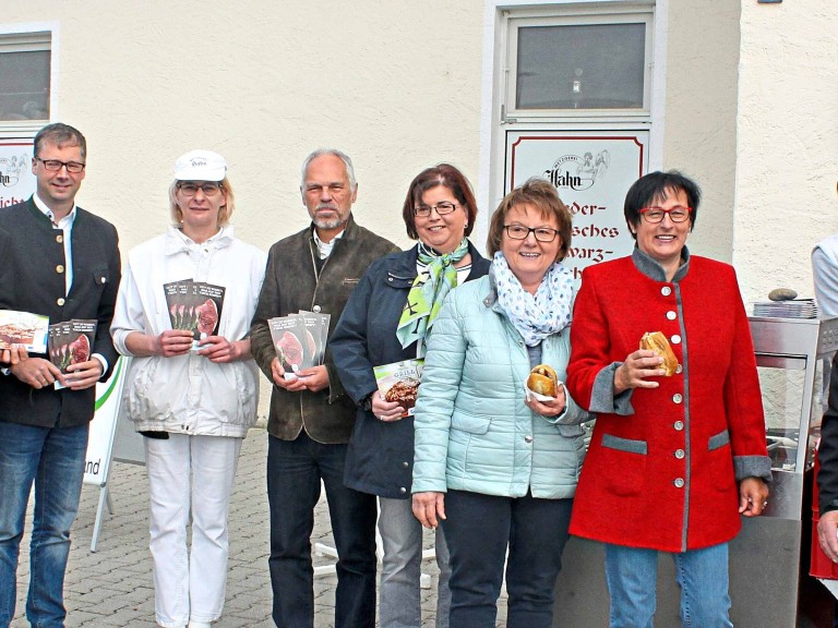 Personengruppe mit Broschüren und Grillwürstl