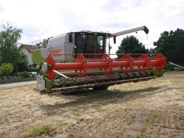 Ein Mähdrescher fährt von der Straße auf ein Feld.