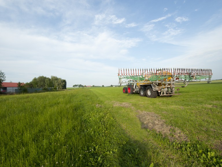 Ein Traktor mit Güllefass auf einer Wiese.