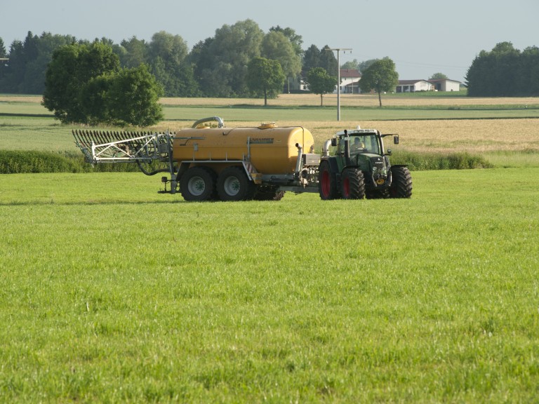 Ein Landwirt bringt Gülle auf seiner Wiese aus. 