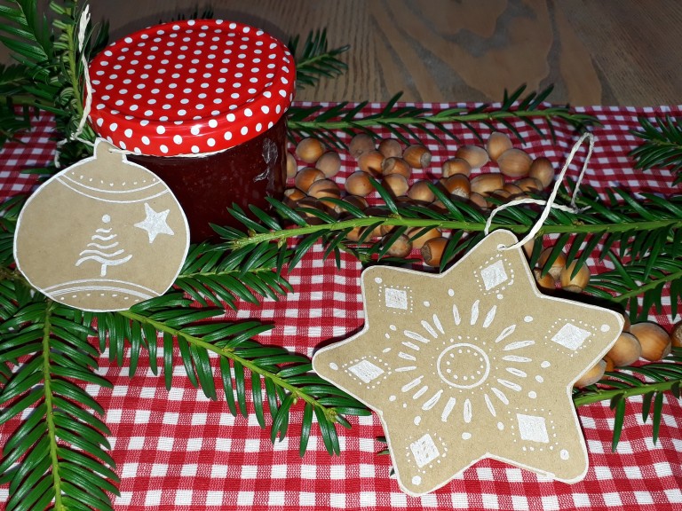 Ein selbstgebastelter, liebevoll gestalteter Geschenkanhänger in Stern-, Kugel- oder Tannenbaumform aus einem alten Karton anstelle einer gekauften Weihnachtskarte.