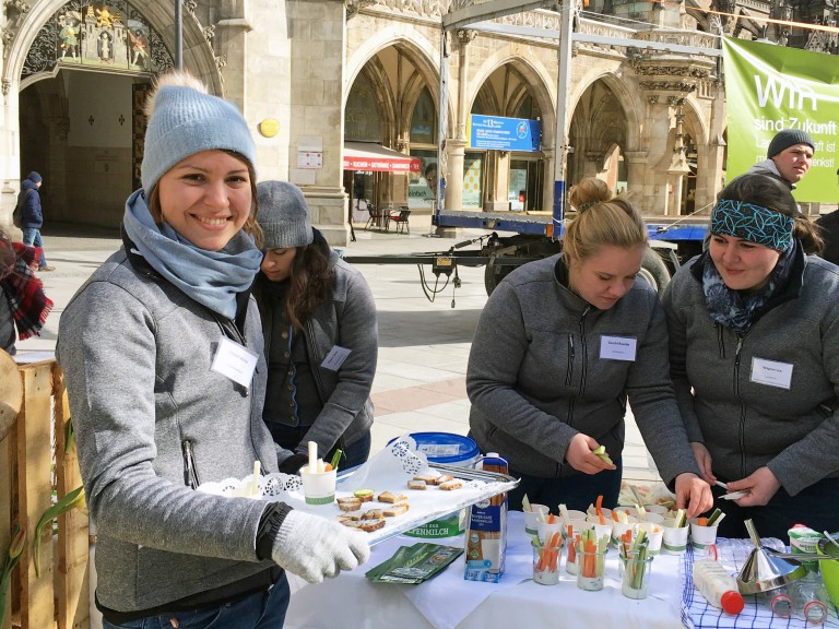 Junge Teilnehmerinnen und Teilnehmer des Herrschinger Grundkures informieren am Marienplatz über regionale Lebensmittel.