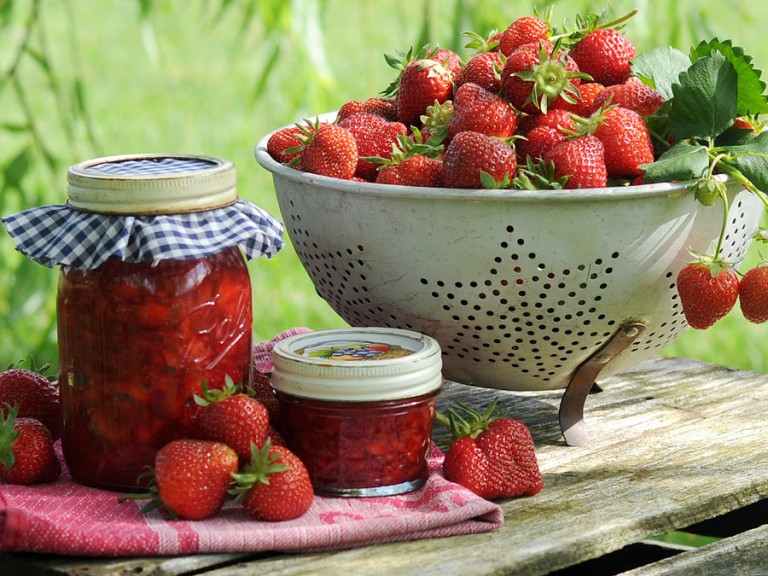 Eine Schüssel Erdbeeren steht auf einem Tisch im Garten.