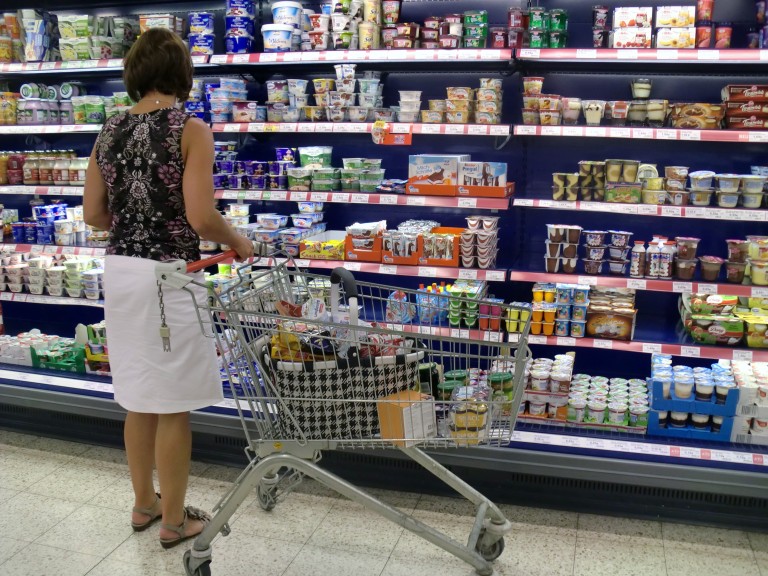 Eine Frau beim einkaufen im Supermarkt vor dem Kühlregal.