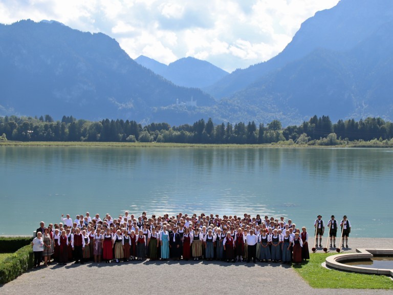 250 Chorsängerinnen und Sänger beim Gruppenbild vor dem Forggensee mit Alpenpanorama und dem Schloss Neuschwanstein im Hintergrund