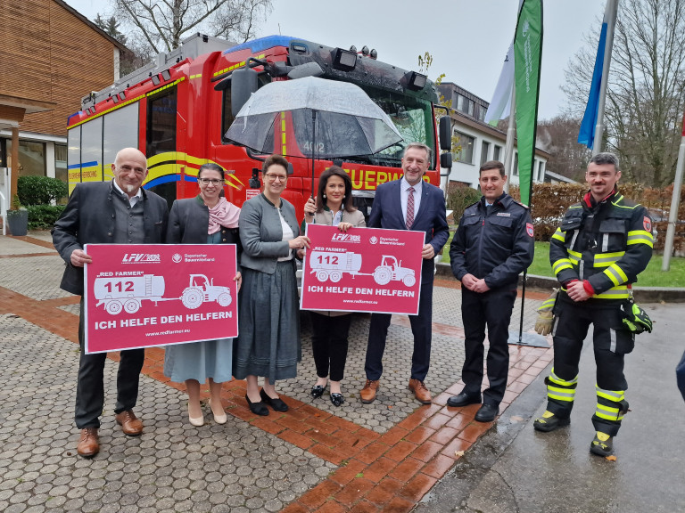 Ministerin Kaniber, Christine Singer, Gütther Felßner stehen mit Feuwehrleuten vor einem Feuerwehrauto