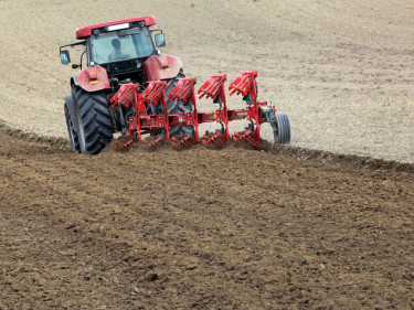 Traktor zieht pflug über einen Acker