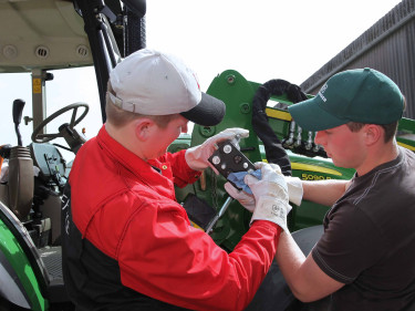 Zwei junge Landwirte arbeiten gemeinsam an einem Traktor