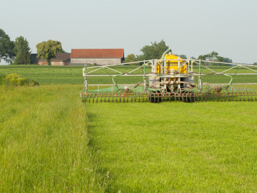 Ein Schlepper düngt auf einer grünen Wiese