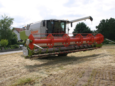 Ein Mähdrescher fährt von der Straße auf ein Feld. 