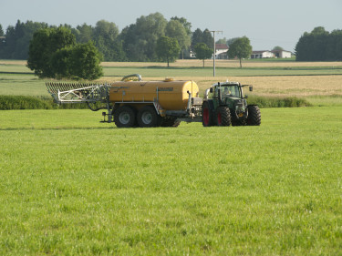 Ein Landwirt bringt Gülle auf seiner Wiese aus. 
