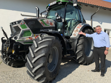Bauernpräsident Heidl steht vor dem Traktor der #EssenAusBayern Kampagne. 
