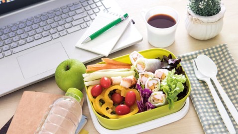 Lunchbox mit gesunden Snacks auf einem Schreibtisch mit Laptop