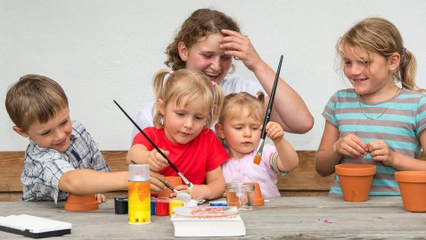 Kinder spielen mit Wassermalfarben an einem Tisch