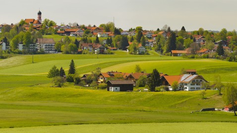 Landschaft in Bayern mit Dorf, Bauernhöfen und grünen Wiesen