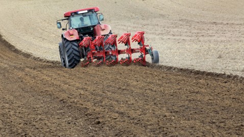 Traktor zieht pflug über einen Acker