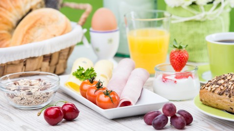 Reichgedeckter Frühstückstisch mit Schinken, Tomaten, Saft