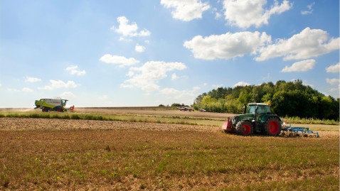 Mähdrescher und Traktor bei der Ernte auf Feldern in Bayern