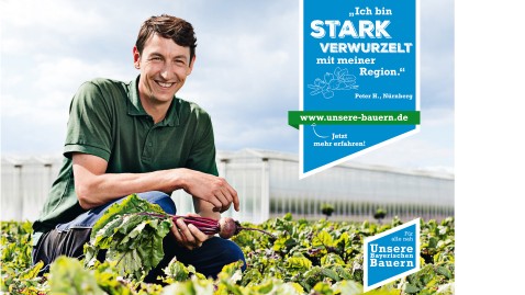 Ein Bauer sitzt über seinem Gemüsefeld und hält eine frische Rübe in die Kamera