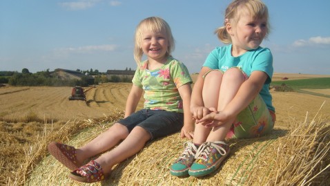 Kinder auf Strohballen in Hof