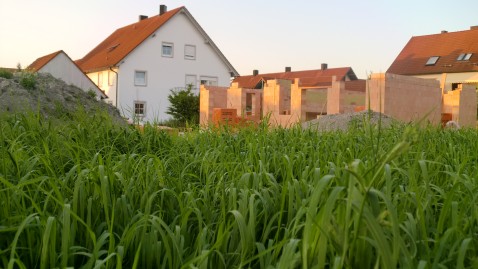 Hausbau, im Vordergrund ein Maisfeld