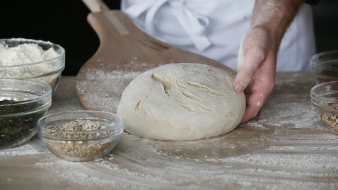 Im Backdorf bei Häussler schiebt ein Bäcker einen Laib Brot auf seinen Backschieber