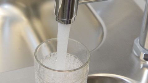 Aus dem Wasserhahn wird Wasser in ein Glas gefüllt