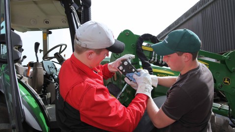 Zwei junge Landwirte arbeiten gemeinsam an einem Traktor