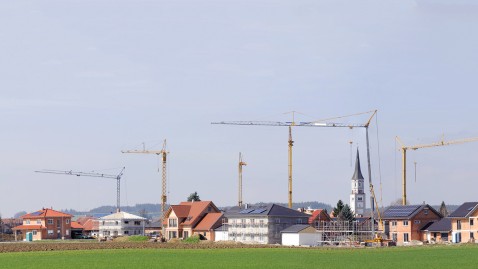 Auf den Feldern rund um ein Dorf werden neue Häuser gebaut und Flächen so verbraucht