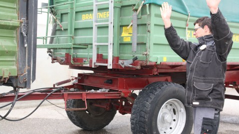 Ein angegendet Landwirt bei der Einweisung eines Anhängers