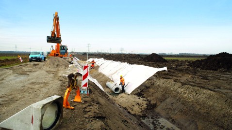 Bagger und Bauarbeiter heben eine lange Grube aus