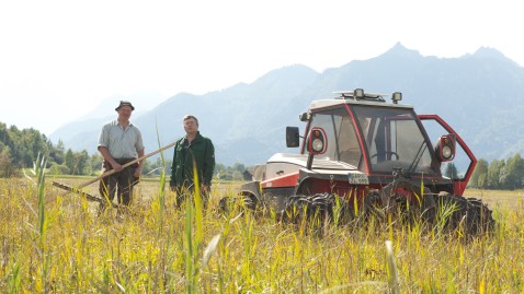 Zwei Landwirte unterhalten sich auf einen Feld. Im Hintergrund ein Schlepper zu sehen
